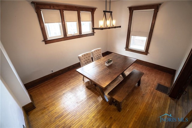 unfurnished dining area with visible vents, baseboards, and hardwood / wood-style floors