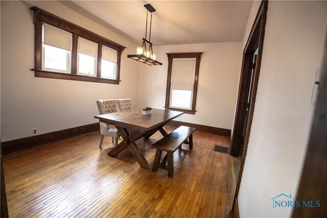 dining area with visible vents, baseboards, and hardwood / wood-style flooring