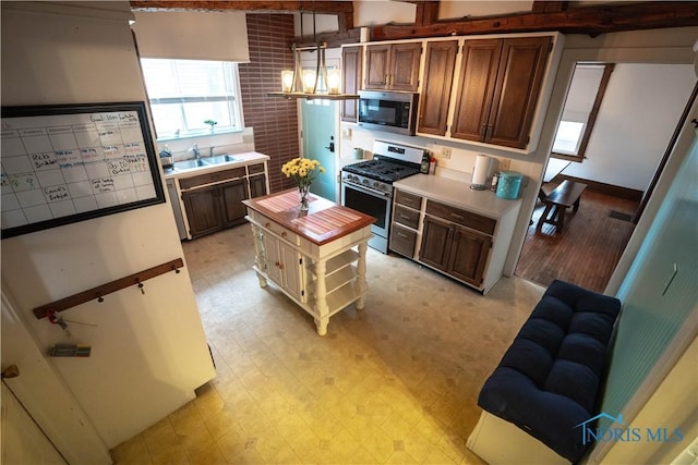 kitchen featuring a center island, light floors, hanging light fixtures, stainless steel appliances, and a sink