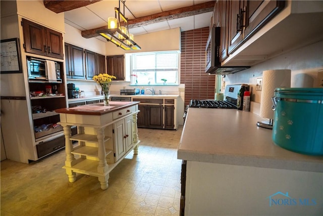 kitchen featuring dark brown cabinets, a kitchen island, beam ceiling, appliances with stainless steel finishes, and open shelves