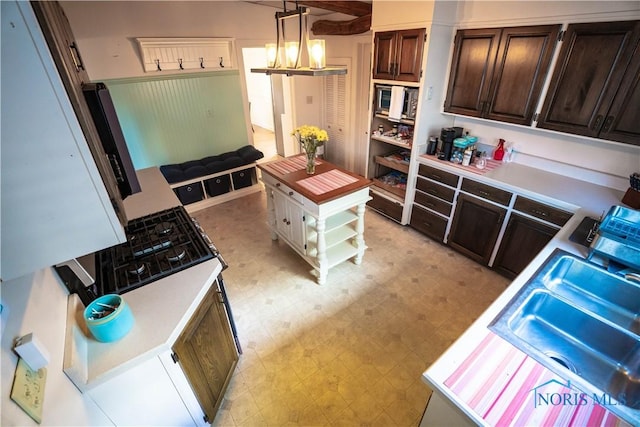 kitchen with open shelves, stainless steel microwave, a sink, light floors, and dark brown cabinets