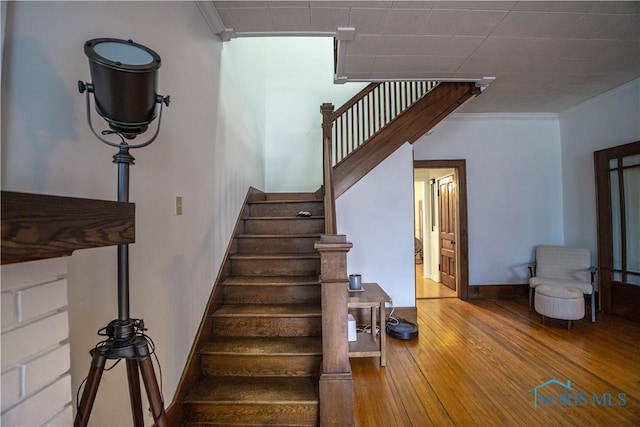 stairs with baseboards, crown molding, and hardwood / wood-style flooring