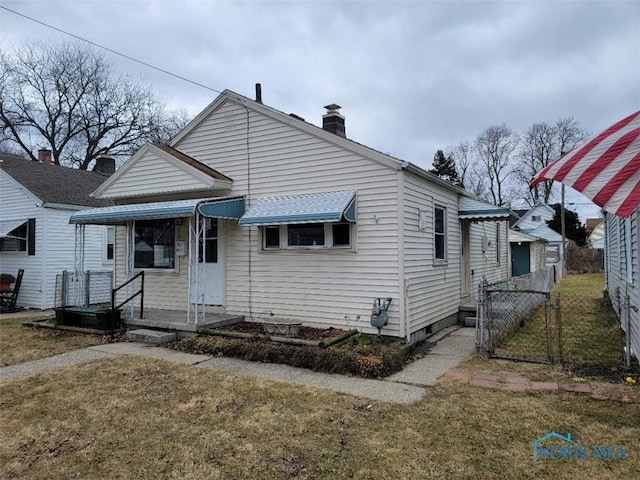 bungalow-style house with a gate, a chimney, a front yard, and fence