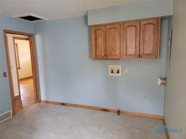 washroom with visible vents, baseboards, hookup for a washing machine, cabinet space, and a textured ceiling