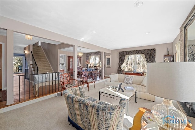 living area featuring a notable chandelier, carpet flooring, and stairway