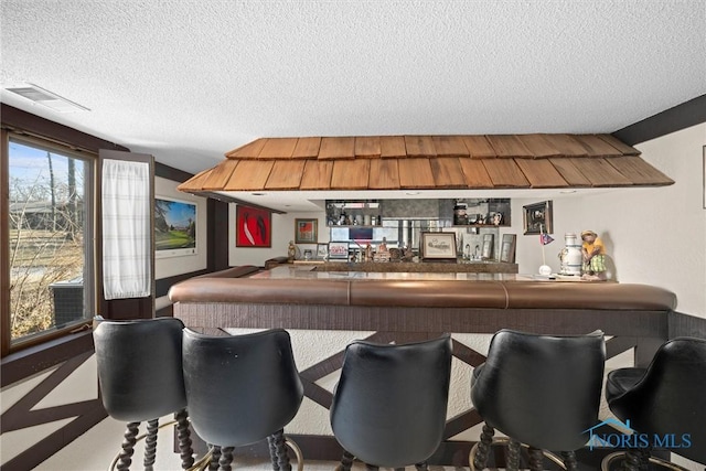 bar featuring visible vents, bar area, and a textured ceiling