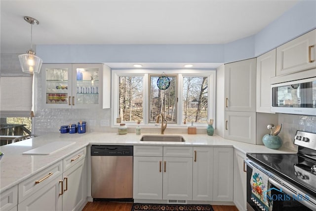 kitchen featuring visible vents, a sink, appliances with stainless steel finishes, white cabinets, and decorative backsplash