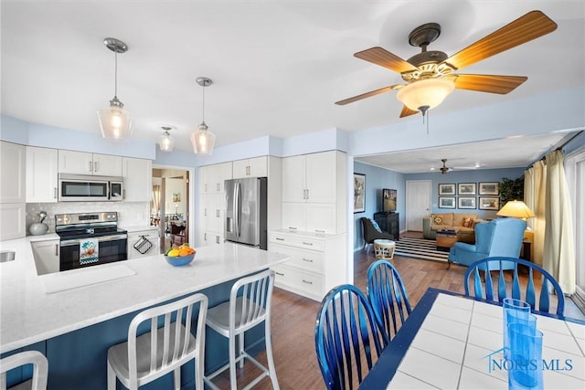 kitchen with light countertops, a ceiling fan, open floor plan, and stainless steel appliances