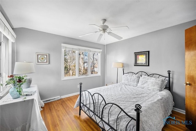 bedroom featuring visible vents, wood finished floors, baseboards, and lofted ceiling