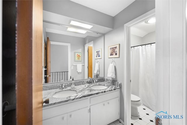 full bath featuring a shower with shower curtain, double vanity, toilet, and a sink