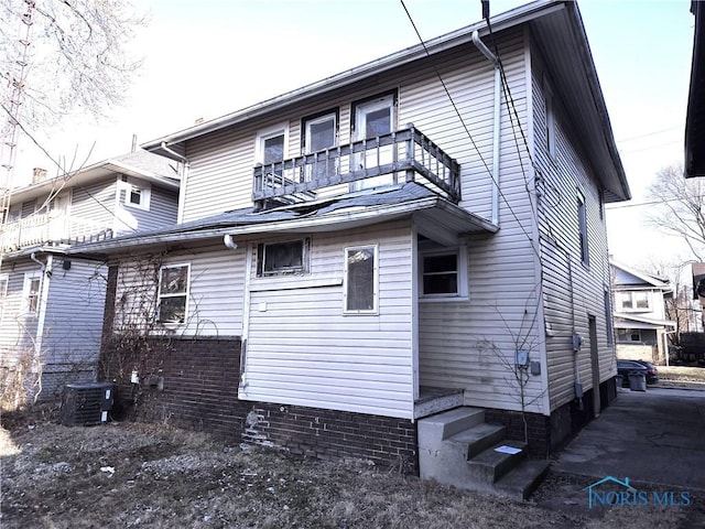 rear view of house with central air condition unit and a balcony