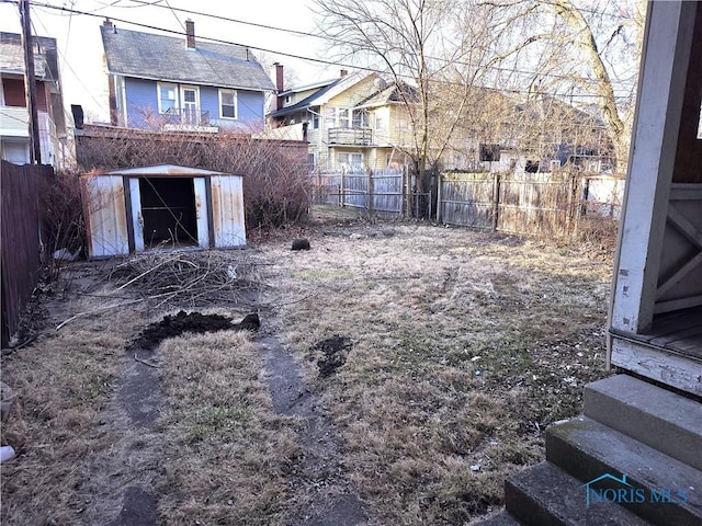 view of yard with an outbuilding, a fenced backyard, and a shed