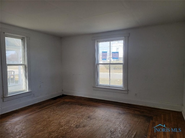 unfurnished room with baseboards and dark wood-style flooring