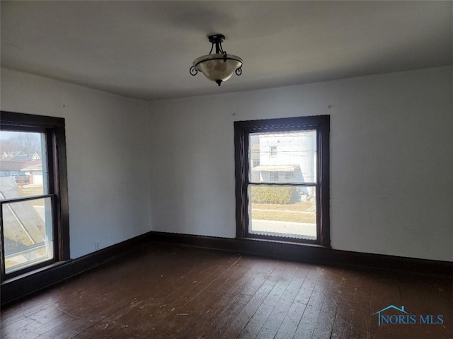 unfurnished room with dark wood-style floors and baseboards