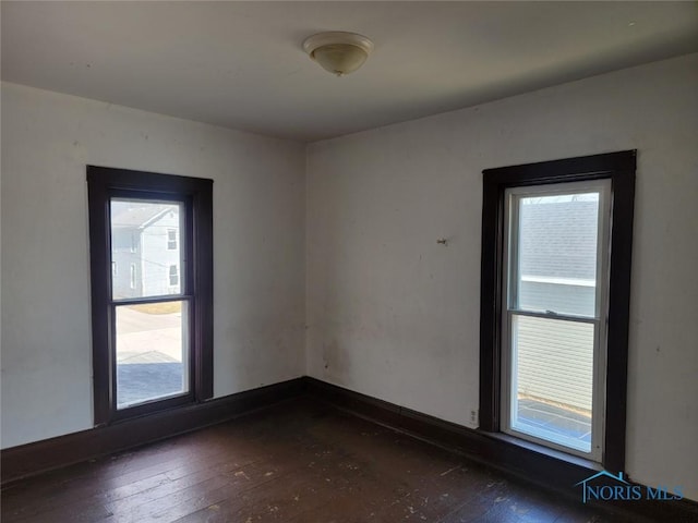 empty room with dark wood-style floors and baseboards