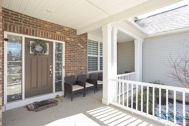 doorway to property with brick siding and covered porch