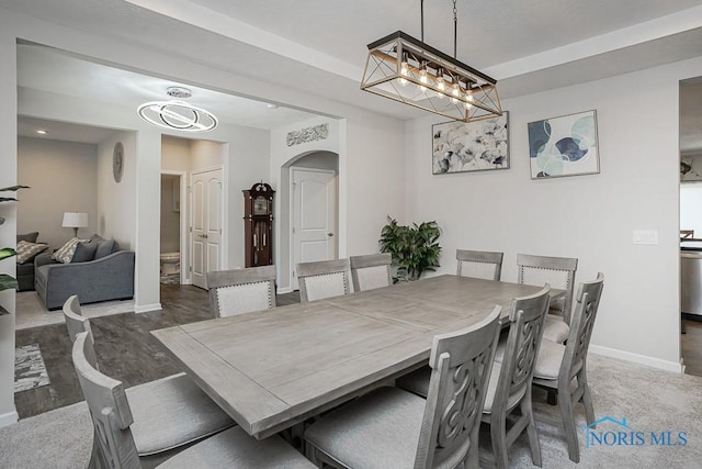 dining area with wood finished floors, baseboards, arched walkways, and a chandelier