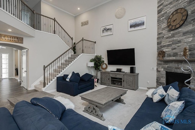 living area featuring baseboards, a high ceiling, arched walkways, ornamental molding, and stairs