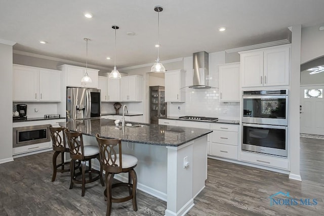 kitchen featuring a sink, dark wood-type flooring, appliances with stainless steel finishes, crown molding, and wall chimney exhaust hood