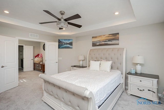 bedroom with recessed lighting, visible vents, a raised ceiling, and light colored carpet