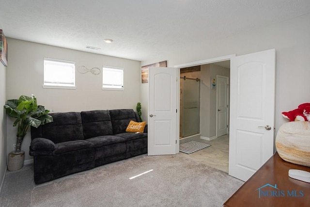 living area featuring light carpet, visible vents, and a textured ceiling