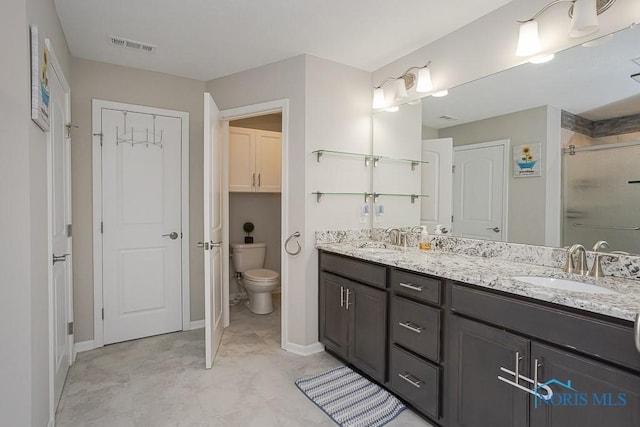 bathroom with double vanity, visible vents, toilet, and a sink