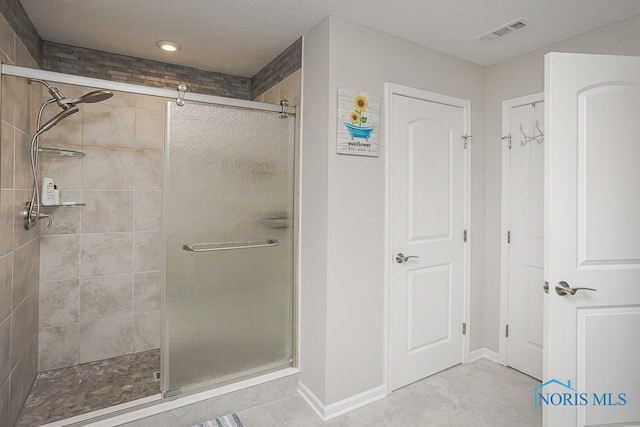 bathroom with a shower stall, baseboards, visible vents, and a textured ceiling