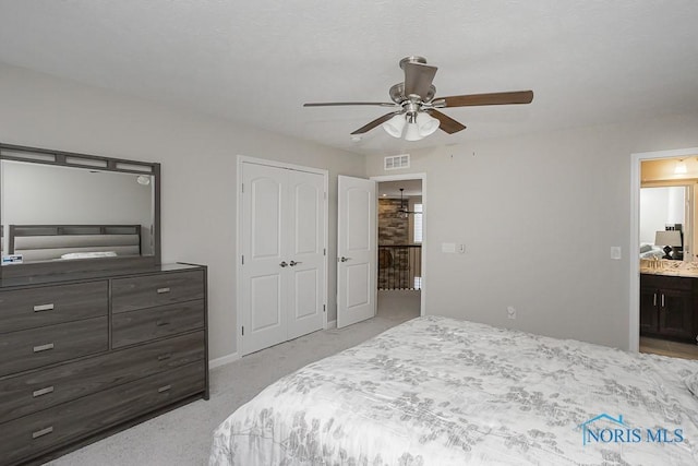 bedroom with a closet, visible vents, ensuite bath, and a ceiling fan