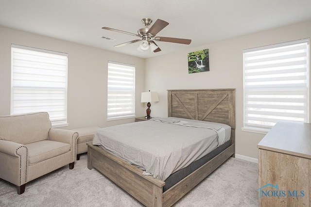 bedroom featuring ceiling fan, baseboards, visible vents, and light carpet