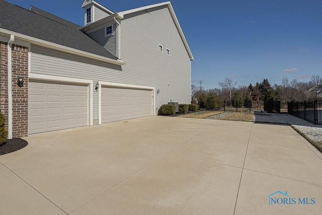 view of property exterior featuring driveway, roof with shingles, and fence