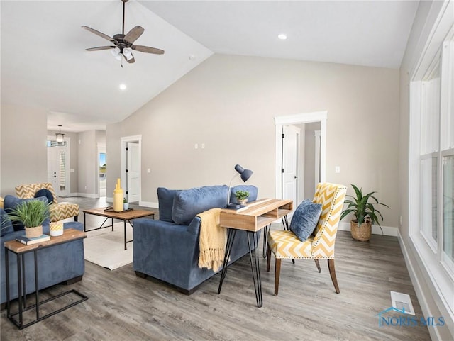 living area with visible vents, wood finished floors, baseboards, and vaulted ceiling