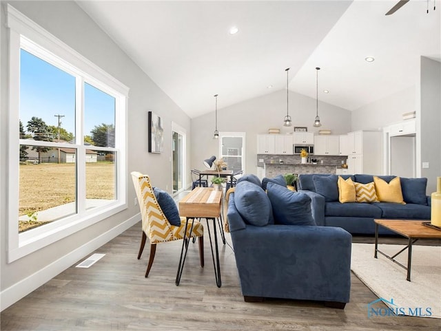 living area featuring vaulted ceiling, baseboards, visible vents, and light wood finished floors