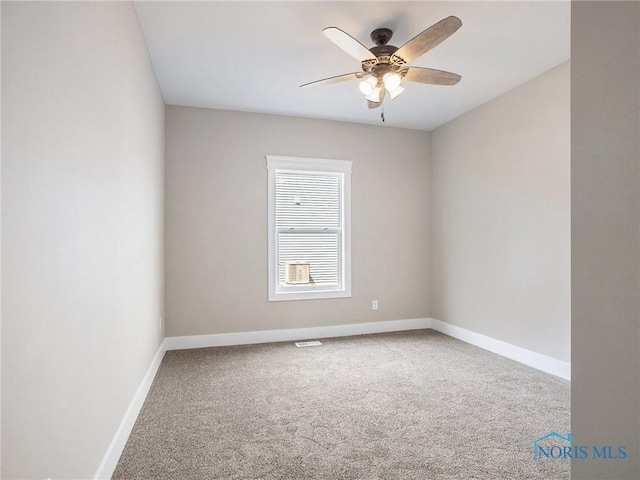 carpeted spare room featuring a ceiling fan and baseboards