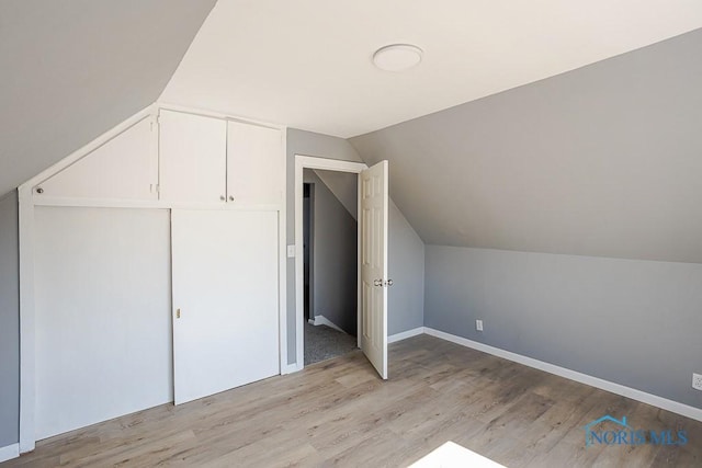 bonus room with light wood-type flooring, lofted ceiling, and baseboards