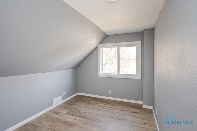 bonus room with visible vents, baseboards, wood finished floors, and vaulted ceiling