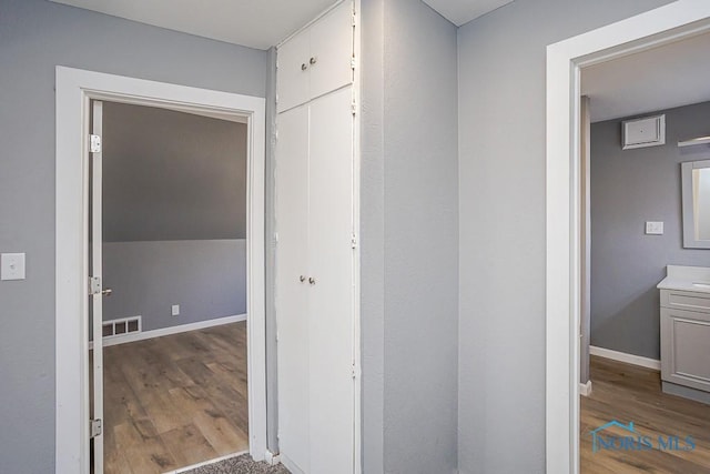 corridor with visible vents, baseboards, and wood finished floors