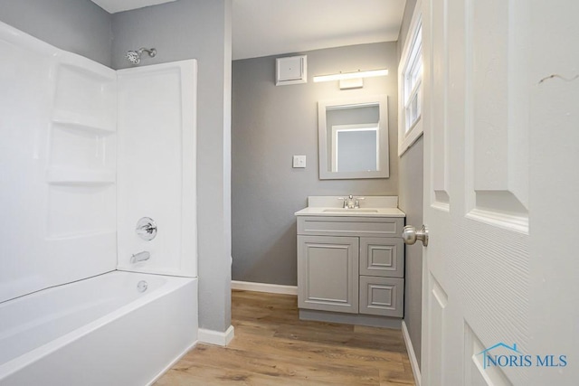 bathroom with shower / bath combination, baseboards, wood finished floors, and vanity