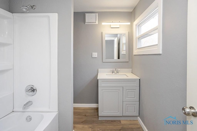 full bath featuring vanity, wood finished floors, baseboards, and shower / bathtub combination