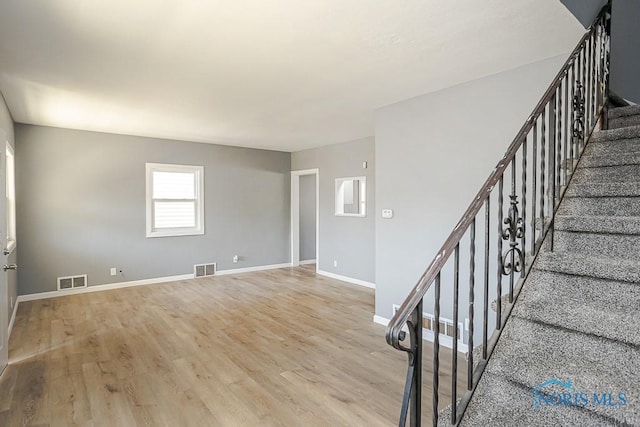 staircase featuring visible vents, baseboards, and wood finished floors