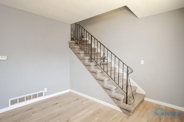 staircase with visible vents, baseboards, and wood finished floors