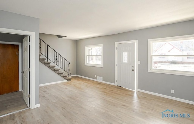 foyer with stairs, visible vents, wood finished floors, and baseboards