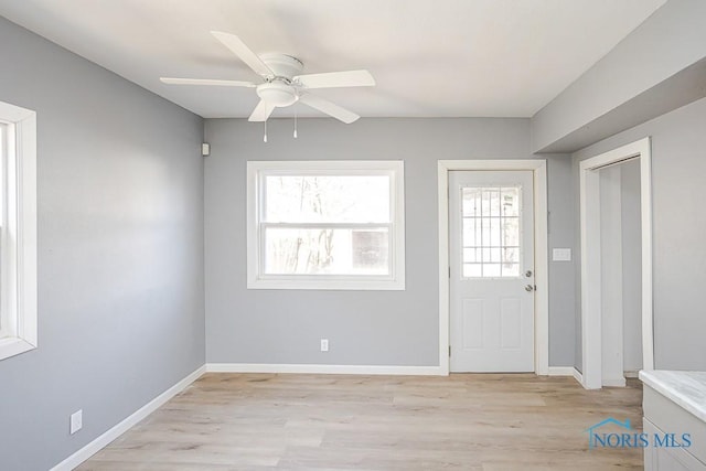 foyer entrance with baseboards, light wood-style floors, and ceiling fan