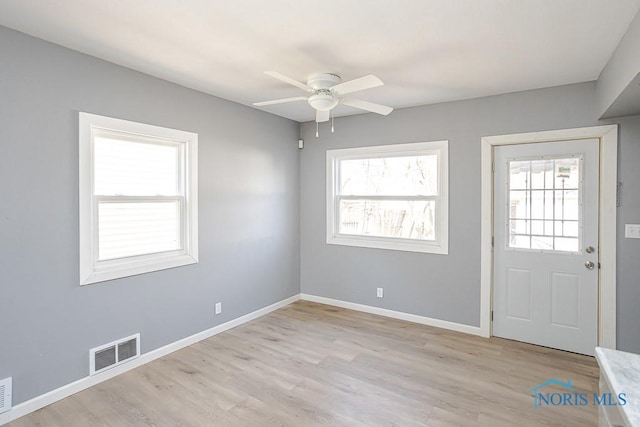 foyer with visible vents, baseboards, ceiling fan, and light wood-style flooring