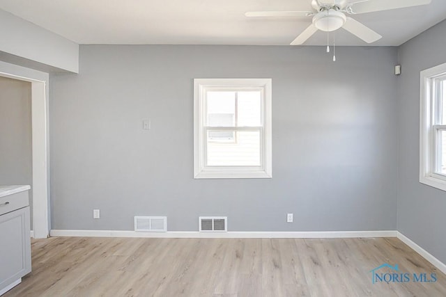 empty room featuring visible vents, baseboards, light wood-style floors, and a ceiling fan