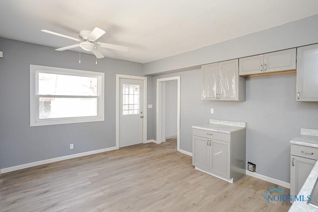 kitchen with baseboards, light countertops, light wood-style floors, and ceiling fan