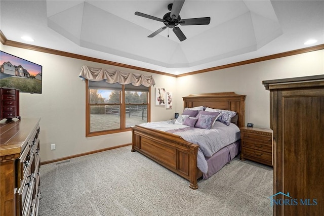 bedroom with crown molding, baseboards, light colored carpet, and a raised ceiling