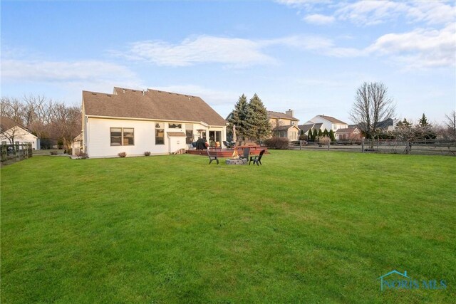 rear view of property featuring a lawn and fence