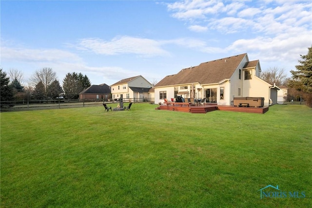 rear view of house with a hot tub, a yard, fence, and a wooden deck