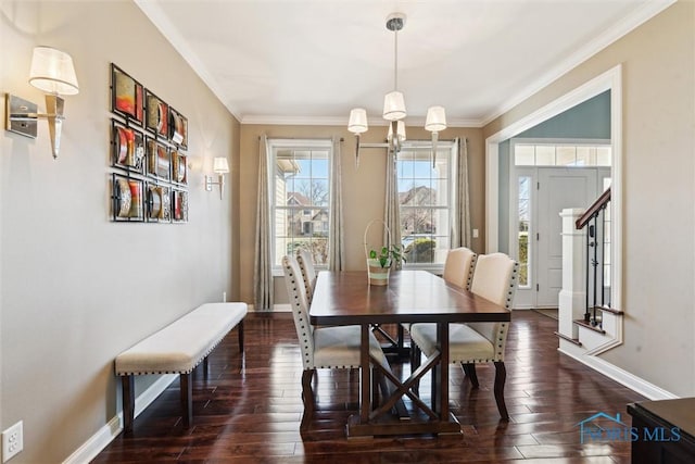 dining space featuring dark wood-type flooring, crown molding, and baseboards