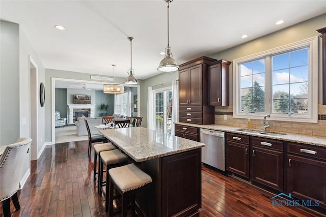 kitchen featuring dishwasher, light stone counters, tasteful backsplash, and a sink